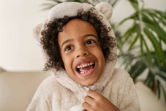 Uma criança vestindo uma roupa de frio com a boca aberta mostrando os dentes. Uma criança vestindo uma roupa de frio com a boca aberta mostrando os dentes.