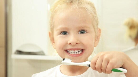 Menino sorrindo, segurando uma escova de dentes em frente ao rosto. Menino sorrindo, segurando uma escova de dentes em frente ao rosto.