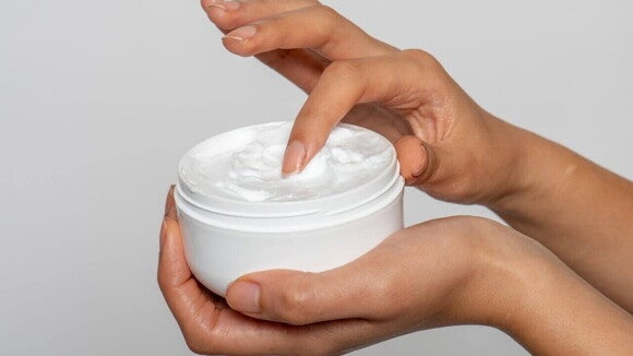 Aplicação de creme hidratante com as pontas dos dedos, essencial para o tratamento da dermatite APLV e para manter a barreira cutânea.