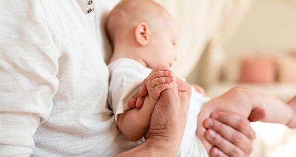 Homem embalando gentilmente um bebê no colo, mostrando o terno vínculo entre pai e filho Homem embalando gentilmente um bebê no colo, mostrando o terno vínculo entre pai e filho