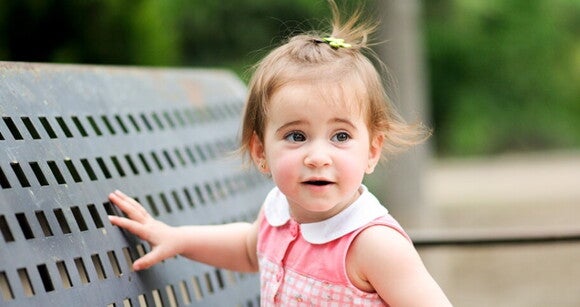 Menina de aproximadamente 2 anos usando vestido cor de rosa sentada no banco de um parque. Menina de aproximadamente 2 anos usando vestido cor de rosa sentada no banco de um parque.