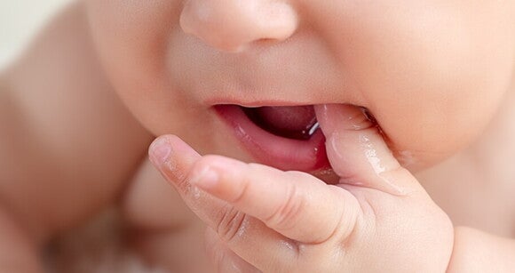 Foto focada no rosto do bebê que está com a mãozinha na boca Foto focada no rosto do bebê que está com a mãozinha na boca