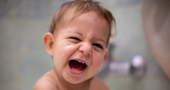 Bebê com diastema sorrindo enquanto toma banho de banheira. Bebê com diastema sorrindo enquanto toma banho de banheira.