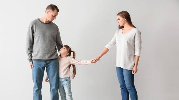 Uma família em conflito, representada por um casal e uma criança. A menina está no meio, segurando as mãos de ambos os pais, que olham em direções opostas. A imagem retrata o drama de uma família em processo de separação e a importância de entender como funciona a guarda unilateral. Uma família em conflito, representada por um casal e uma criança. A menina está no meio, segurando as mãos de ambos os pais, que olham em direções opostas. A imagem retrata o drama de uma família em processo de separação e a importância de entender como funciona a guarda unilateral.