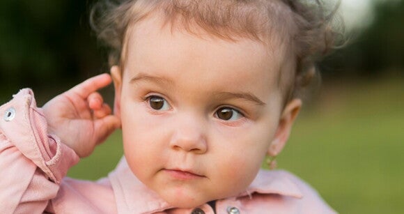 Bebê usando roupa cor de rosa e passando a mão na orelha. Bebê usando roupa cor de rosa e passando a mão na orelha.
