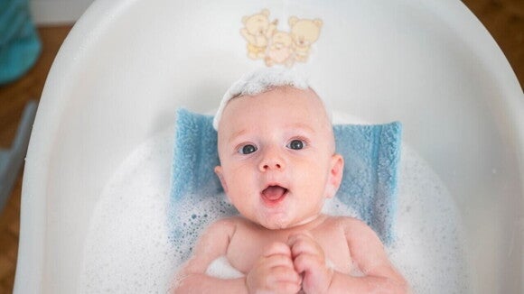 Um bebê dentro de uma banheira, com a cabeça ensaboada Um bebê dentro de uma banheira, com a cabeça ensaboada