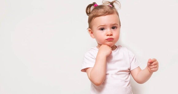 Menina de aproximadamente dois anos posando para a foto usando camiseta branca em um ambiente com fundo branco. Menina de aproximadamente dois anos posando para a foto usando camiseta branca em um ambiente com fundo branco.