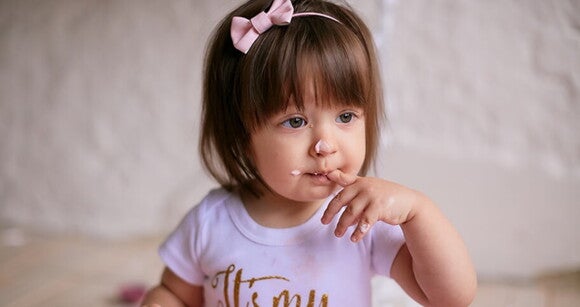 Menina de aproximadamente dois anos de olhos claros usando tiara de lacinho rosa e com o dedo na boca. Menina de aproximadamente dois anos de olhos claros usando tiara de lacinho rosa e com o dedo na boca.