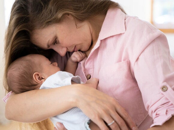 É possível prolongar a licença-amamentação? Foto de mamãe segurando bebê de perto.