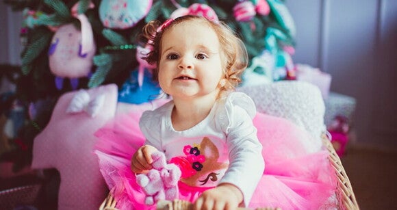 Menina de aproximadamente 1 ano usando vestido rosa e segurando um ursinho de pelúcia. Menina de aproximadamente 1 ano usando vestido rosa e segurando um ursinho de pelúcia.
