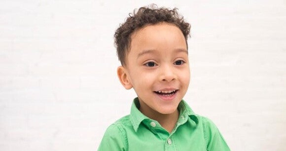 Menino de cabelo enrolado usando camisa verde sorrindo Menino de cabelo enrolado usando camisa verde sorrindo