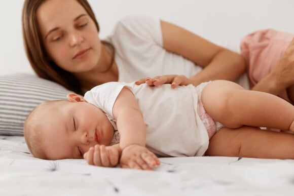 mãe acaricia bebê em cama enquanto ele dorme mãe acaricia bebê em cama enquanto ele dorme