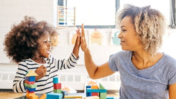 Menininha e mãe brincando juntas, batendo high-five.