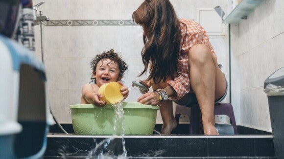Menino se divertindo com a mãe na hora do banho.