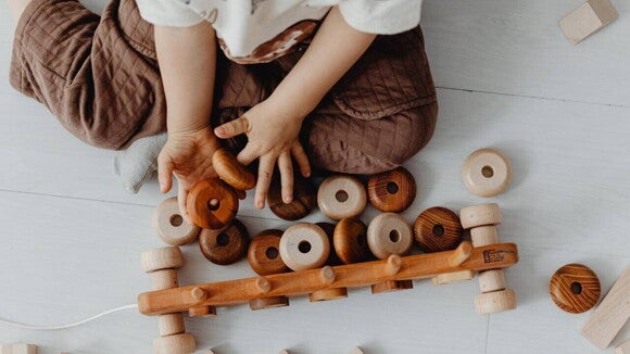 Um bebê sentado no chão brincando com objetos lúdicos.