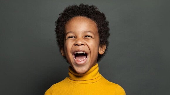 Menino sorridente e radiante vestindo uma blusa gola alta de cor amarela. Menino sorridente e radiante vestindo uma blusa gola alta de cor amarela.