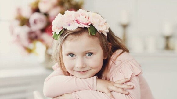 Menina com arco de flores na cabeça vestindo uma blusa rosa e olhando diretamente para a câmera. Menina com arco de flores na cabeça vestindo uma blusa rosa e olhando diretamente para a câmera.