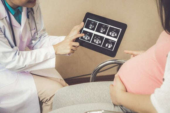 Profissional de saúde mostrando o resultado de um exame de ultrassom para uma mulher grávida Profissional de saúde mostrando o resultado de um exame de ultrassom para uma mulher grávida
