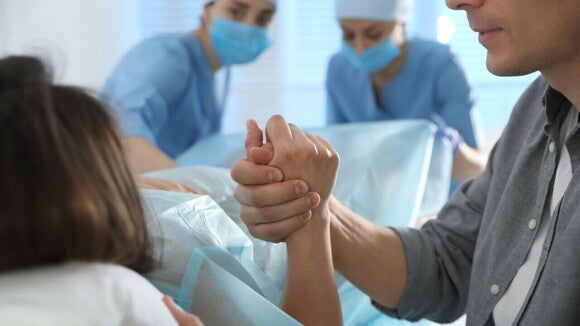 Mão de acompanhante segurando a da gestante durante o parto