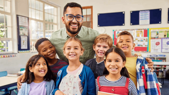 professor e alunos Um professor e um grupo de crianças sorrindo em uma sala de aula.
