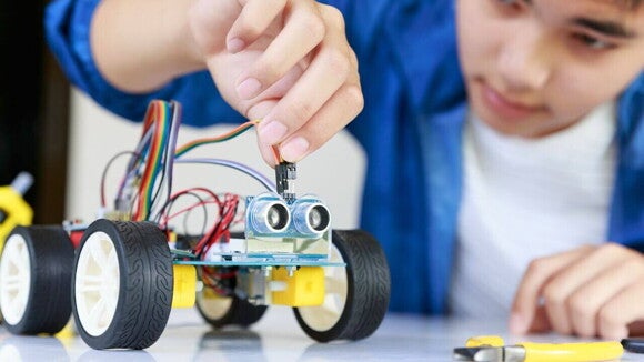 Um rapaz jovem operando um carrinho robótico. Um rapaz jovem operando um carrinho robótico.