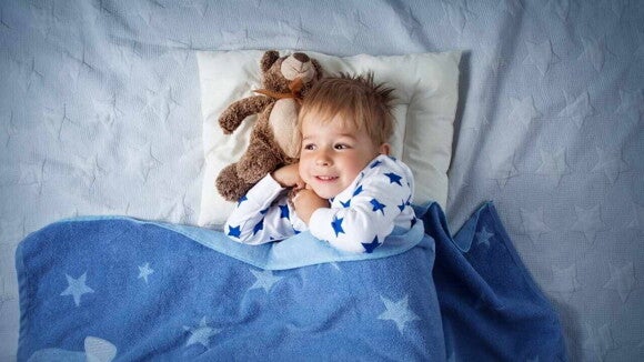 Menino de 2 anos usando pijama estampado com estrelas azuis, deitada em cama confortável com cobertor azul, abraçado em urso de pelúcia, em um quarto iluminado suavemente. Menino de 2 anos usando pijama estampado com estrelas azuis, deitada em cama confortável com cobertor azul, abraçado em urso de pelúcia, em um quarto iluminado suavemente.