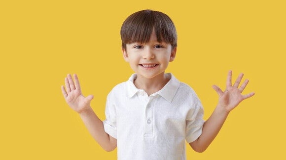 Menino sorrindo com as mãos abertas sobre um fundo amarelo Menino sorrindo com as mãos abertas sobre um fundo amarelo