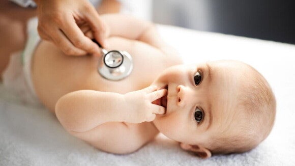 Pediatra examina o peito de um bebê com um estetoscópio. O exame médico é crucial para o diagnóstico e investigação de possíveis sintomas de APLV em crianças.