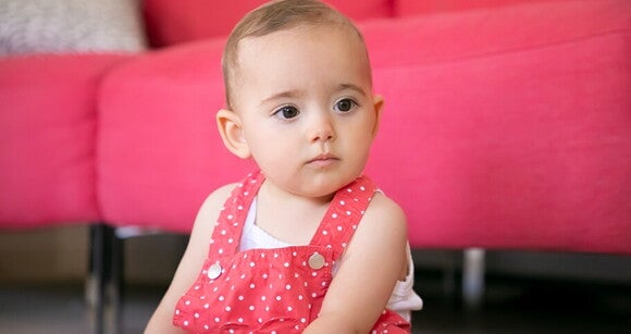 Menina de aproximadamente 1 ano sentada no chão da sala usando um vestido cor de rosa com bolinhas brancas. Menina de aproximadamente 1 ano sentada no chão da sala usando um vestido cor de rosa com bolinhas brancas.